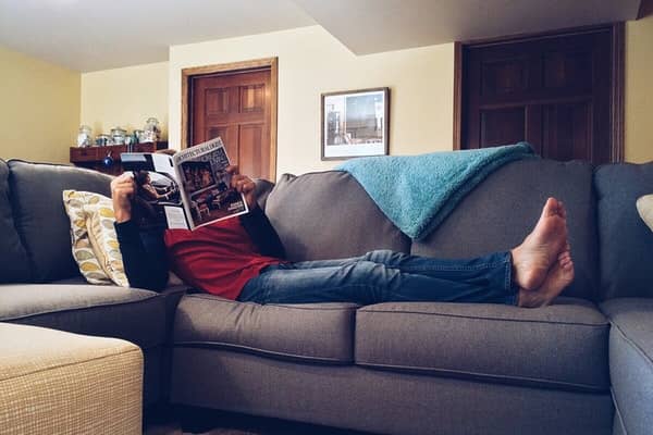 A person relaxing on the sofa with a magazine